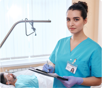 Nurse in blue scrubs writing notes on a clipboard beside a hospital bed with a patient.