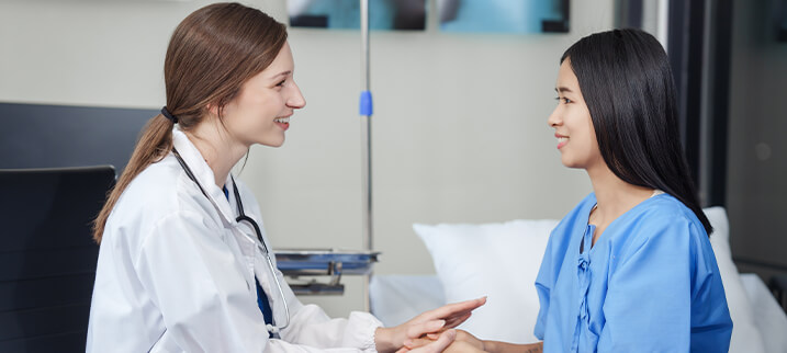 Doctor comforting patient in hospital room, providing care and support in a medical setting.