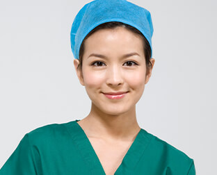 Smiling healthcare professional in green scrubs and blue cap, ready for work in a medical setting.