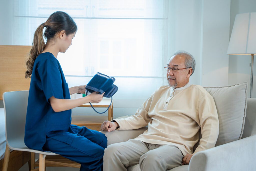 Nurse preparing to check blood pressure for elderly man in home care setting.