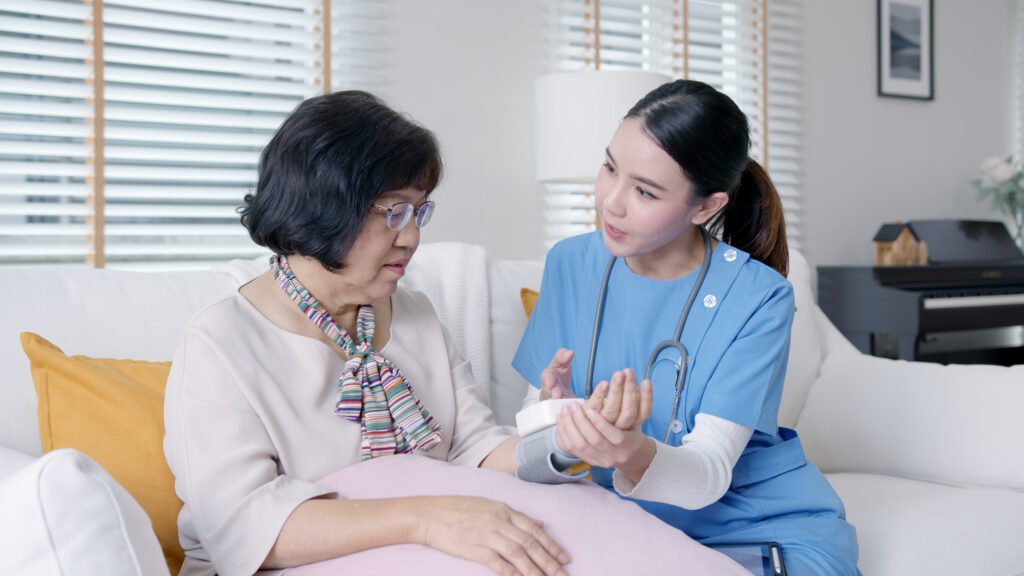 Nurse checking elderly woman's blood pressure at home, providing healthcare and support.