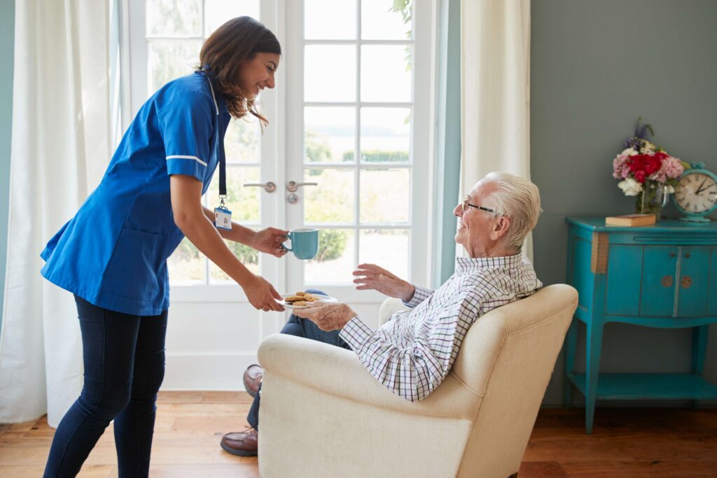 nurse-serving-a-cup-of-tea-to-a-senior-man-at-home-2024-10-19-02-53-00-utc